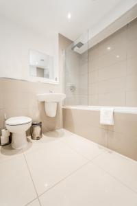 a white bathroom with a toilet and a sink at Apartments Near The O2 in London