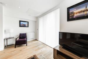 a living room with a tv and a chair at Apartments Near The O2 in London