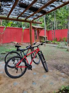 una bicicleta roja está estacionada bajo un edificio en Casa de Sapê, en Arraial d'Ajuda
