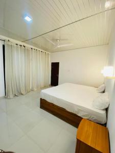 New hotel canel park في بولوناروا: غرفة نوم بيضاء مع سرير وطاولة خشبية