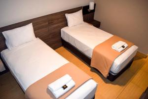two beds in a hotel room with white sheets at Hotel Mega in Lima