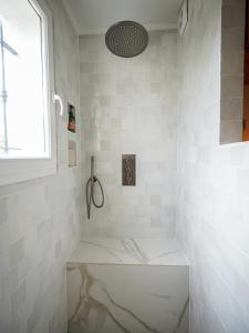 ein weiß gefliestes Bad mit einer Dusche und einem Fenster in der Unterkunft CASA ALBA in Solliès-Pont
