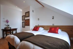 una camera con 2 letti con cuscini rossi di Les Balcons De Riquewihr a Riquewihr