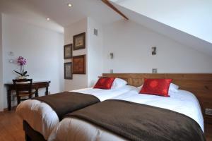 a bedroom with two beds with red pillows at Les Balcons De Riquewihr in Riquewihr