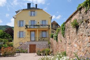 een geel huis aan de zijkant van een muur bij Les Balcons De Riquewihr in Riquewihr