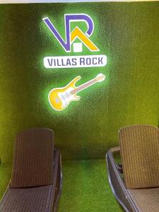 two chairs in front of a wall with a guitar on it at Villasrock2022 in San Clemente