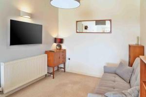 a living room with a couch and a flat screen tv at Ground Floor Sea View Apartment Private Terrace in Torquay