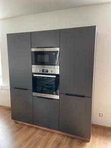 a gray cabinet with a microwave and an oven at Studio avec WC et SDB privés dans Grande maison à côté du campus Artem - Thermal et Parc des Expos in Vandoeuvre-lès-Nancy