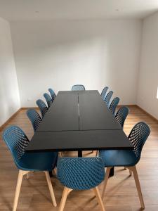 a conference room with a black table and blue chairs at Studio avec WC et SDB privés dans Grande maison à côté du campus Artem - Thermal et Parc des Expos in Vandoeuvre-lès-Nancy