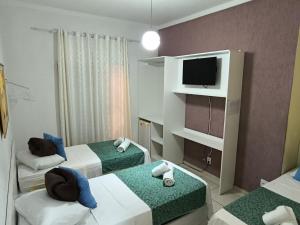 a hotel room with two beds and a television at Brotas Suítes Belo Quinto & Spazzio Bloco 2 in Brotas