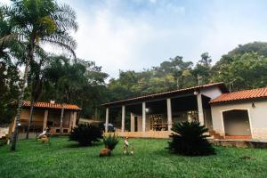 uma casa com duas pessoas na relva em frente dela em Rancho Divino Espírito Santo- Beira Lago Corumbá IV em Alexânia
