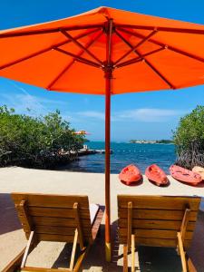 巴魯的住宿－Hotel Playa Scondida，海滩上的橙色遮阳伞和2艘皮艇