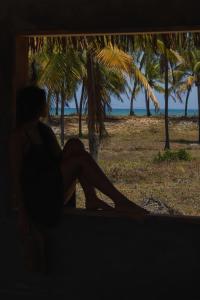 馬塔迪聖若昂的住宿－Blue praia de Santo Antônio，坐在窗户旁的一位女士,她看着海滩