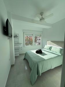 a white bedroom with a bed and a ceiling fan at Apartamento León céntrico, moderno y muy equipado in Almansa