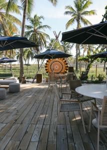 una terraza con mesas, sillas y sombrillas en Blue praia de Santo Antônio en Mata de Sao Joao