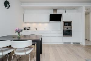 una cucina con armadi bianchi, tavolo e sedie di Dream Stay - 2 Porto Franco Apartments near Old Town a Tallinn