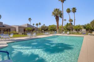 a large swimming pool with chairs and palm trees at Palm Springs Condo 3 Fenced Patios, Pool Access in Palm Springs