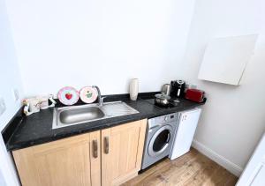 a kitchen with a sink and a washing machine at Cute Studio Garden Flat, 5 min to tube in London
