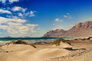 una playa de arena con montañas en el fondo y el océano en La Casita Surf en Famara