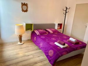 um quarto com uma cama roxa com almofadas e um candeeiro em Maison 180m2, jardin clos, 2 terrasses, 5 mn Dinan em Vildé-Guingalan
