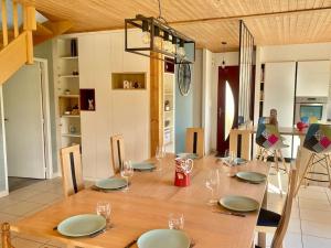 uma mesa de madeira com pratos e copos de vinho em Maison 180m2, jardin clos, 2 terrasses, 5 mn Dinan em Vildé-Guingalan