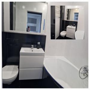 La salle de bains blanche est pourvue d'un lavabo, de toilettes et d'une baignoire. dans l'établissement Apartament XIII piętro STADION NARODOWY, à Varsovie
