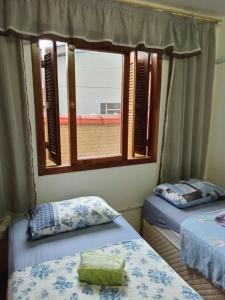 ノヴォ・アンブルゴにあるApartamento das Azaléias térreoのベッド2台と窓が備わる客室です。