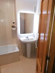 a white bathroom with a sink and a bath tub at Dúplex Unquera. Piscina, garaje. in Unquera