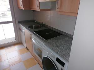 a kitchen with a sink and a washing machine at Dúplex Unquera. Piscina, garaje. in Unquera +3 photos