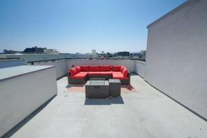 a red couch sitting on top of a roof at $3M Penthouse in K-Town with Private Roof Deck in Los Angeles