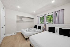 two white beds in a room with a window at Modern Luxe: 4BR Home with Private Jacuzzi in Los Angeles