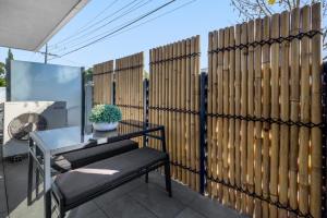 a fence with a bench and a table on a patio at Cosy 1-Bed with Private Balcony By Showgrounds in Melbourne