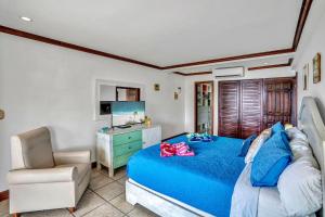 1 dormitorio con 1 cama azul y 1 silla en Newly remodeled unit in Flamingo with sweeping ocean views from big terrace, en Playa Flamingo