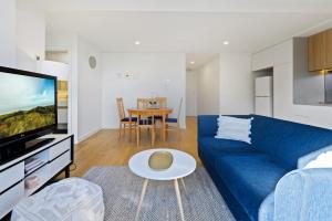 a living room with a blue couch and a table at Cosy 1-Bed with Private Balcony By Showgrounds in Melbourne