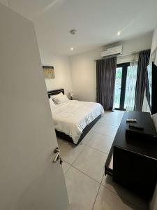 a bedroom with a bed and a desk and a television at The Pine Court in Accra