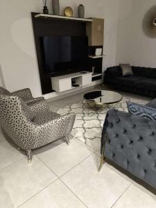 a living room with two chairs and a television at The Pine Court in Accra