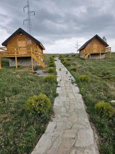 a stone path in front of two wooden buildings at Etno selo Raj na Uvcu in Sjenica