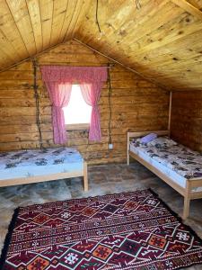 an attic room with two beds and a window at Etno selo Raj na Uvcu in Sjenica