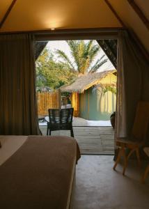 um quarto com uma cama e uma varanda com uma cadeira em Blue praia de Santo Antônio em Mata de São João