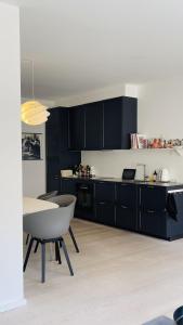 une cuisine avec des armoires noires, une table et des chaises dans l'établissement ApartmentInCopenhagen Apartment 1608, à Copenhague