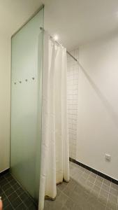 y baño con ducha y cortinas blancas. en ApartmentInCopenhagen Apartment 1608, en Copenhague