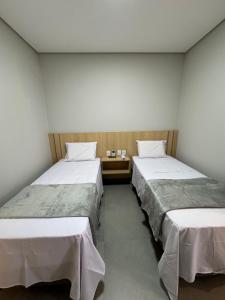 two beds in a room with two tables at HS Hotel in São Paulo