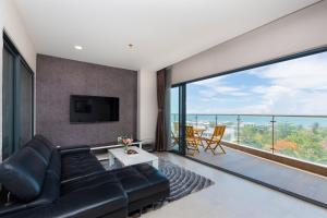 a living room with a black leather couch and a large window at ARIA- VŨNG TÀU - Căn hộ, villa nghỉ dưỡng cao cấp sát bãi biển riêng miễn phí in Vung Tau