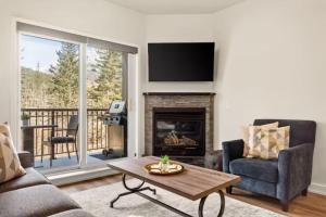 a living room with a fireplace and a tv at Mt Lady MacDonald Suite @ Grande Rockies in Canmore