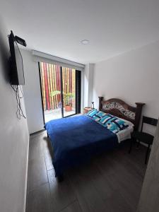 - une chambre avec un lit bleu et une fenêtre dans l'établissement LINDO APTO EN EL NORTE DE ARMENIA MUY BIEN UBICADO, à Armenia