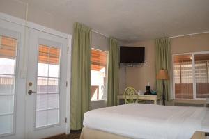 Schlafzimmer mit einem Bett, einem TV und Fenstern in der Unterkunft Mexican Hat Lodge in Mexican Hat