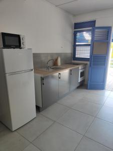 a kitchen with a white refrigerator and a blue door at Les Terrasses de la Wallon Cannelle in Les Trois-Îlets