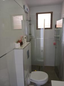 y baño blanco con aseo y ducha. en בלב העיר, en Netanya