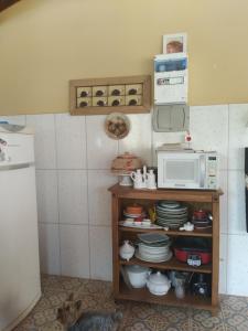 a kitchen with a microwave and a shelf with dishes at casa rústica e aconchegante in Analândia +4 photos
