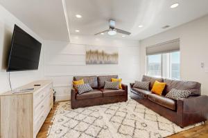 a living room with two leather couches and a flat screen tv at Secret Garden Cottage in Garden City